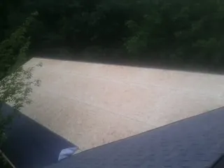 New OSB roof sheathing installed beside an existing shingle roof in Bloomingburg