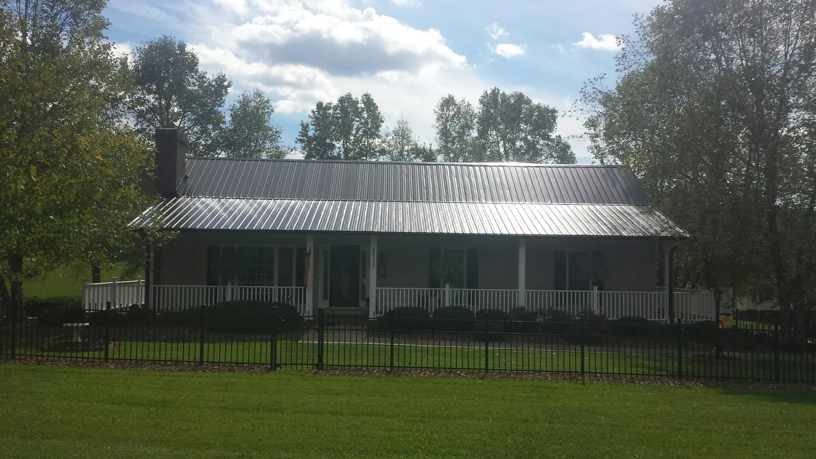 Gray metal roof on a brick ranch with a full width front porch — Gutter Guard Installation work by our crew in Bloomingburg