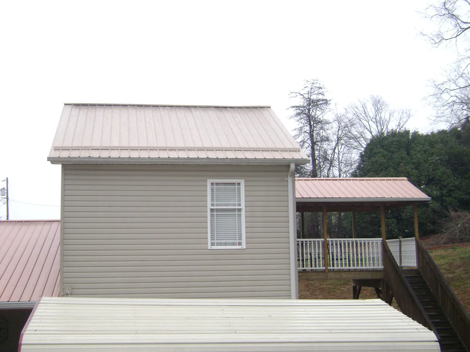 Tan metal roofs on a two story addition and attached porch, from a Roof Replacement job in Bloomingburg