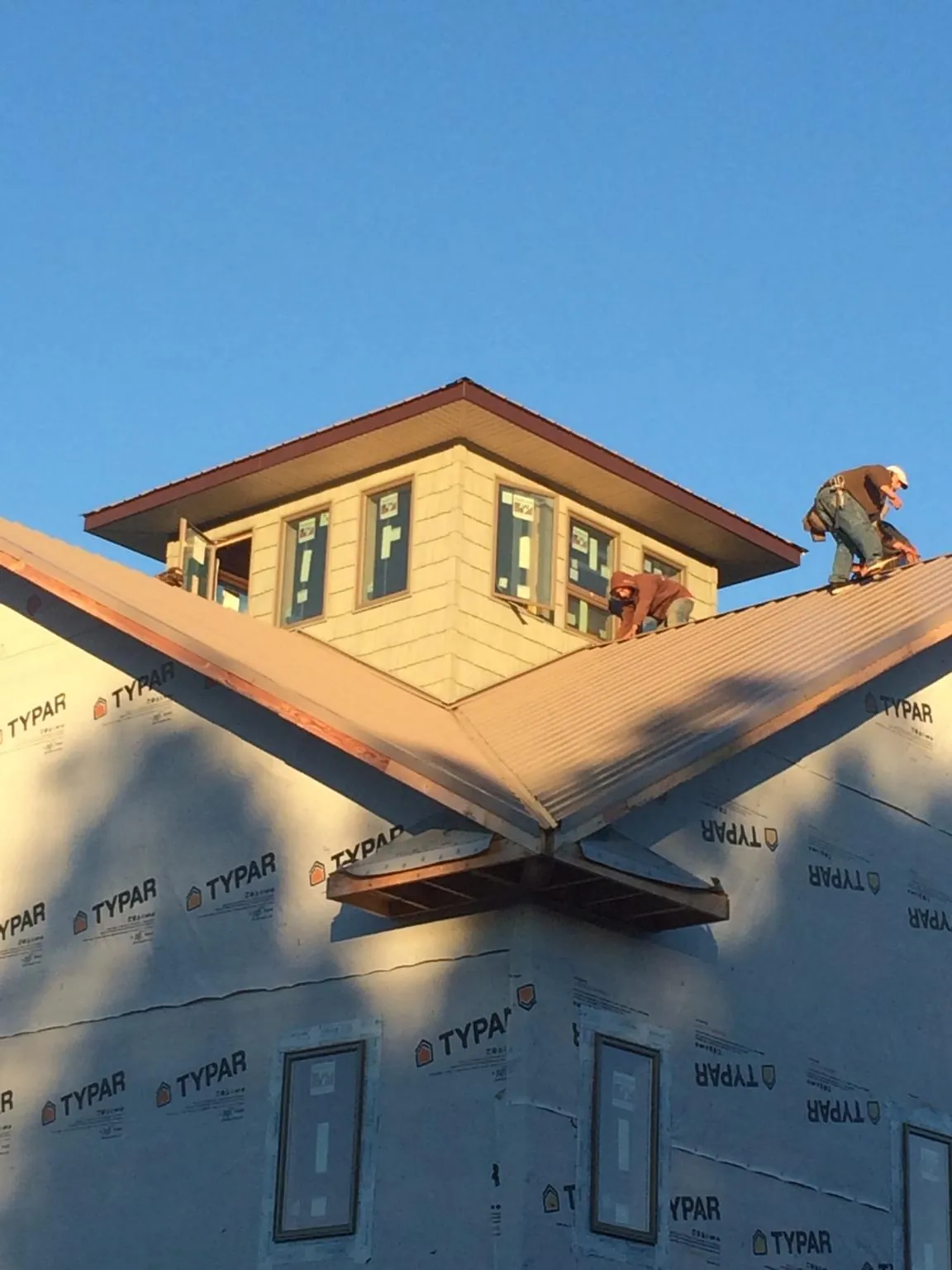 Roofers working around a rooftop cupola on a new metal roof at sunset — Roof Waterproofing in Bloomingburg by Roofing Brothers